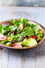 Healthy and tasty salad with tomatoes, olives, cucumber, and lettuce.