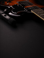 Microphone and electric guitar on a dark background.	