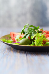 Healthy and tasty salad with tomatoes, olives, cucumber, and lettuce.
