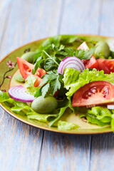 Healthy and tasty salad with tomatoes, olives, cucumber, and lettuce.