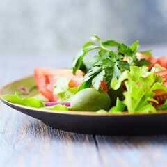 Healthy and tasty salad with tomatoes, olives, cucumber, and lettuce.	