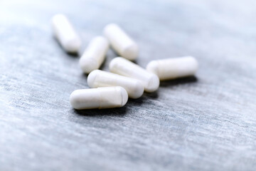 Beta-alanine capsules. Bodybuilding food supplements on wooden background. Soft focus. Close up. Copy space.	