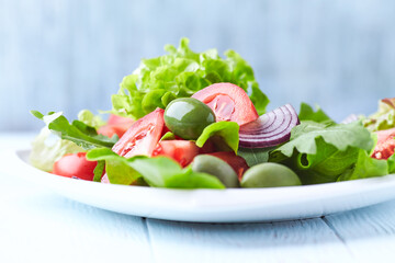 Healthy and tasty salad with tomatoes, olives, cucumber, and lettuce.