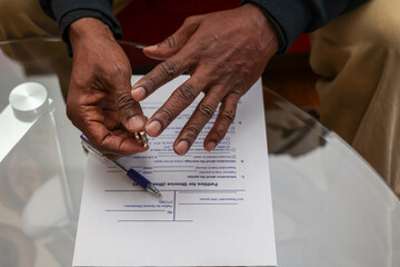 Obraz premium A sad black man signing divorce papers and taking off his wedding ring 