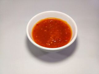 Fiery Indonesian sambal (close-up). A vibrant red chili paste in a white bowl, showcasing its rich texture and intense flavor. This traditional condiment, often homemade, adds a spicy kick to dishes