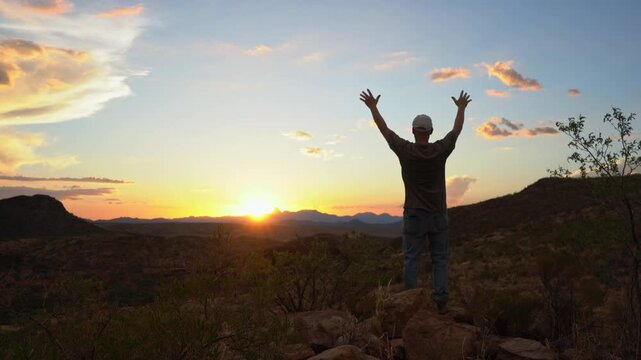 A man praising God from a scenic place at sunset