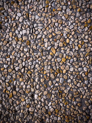 A full frame of small, irregularly shaped pebbles in various shades of brown and grey, embedded in concrete, creating a textured, natural, and rustic surface.