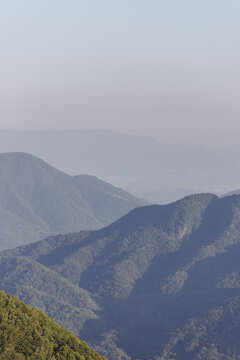View of the rolling mountains fading into the hazy distance under a pale sky, painting a serene landscape with subtle tonal variations, Avellino, Campania, Italy.