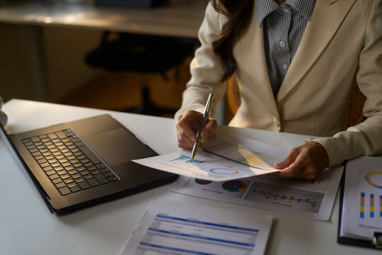 Businesswoman analyzing financial charts and graphs at workplace
