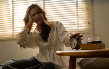 Young Woman Waking Up Late and Turning Off Alarm Clock with Headache