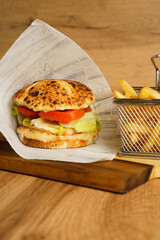 Chicken sandwich with fries on wooden board