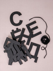 Scattered Russian black letters and black rope on grey background
