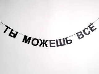 Black letters hang on a string and form the phrase "You can do anything" on a white background
