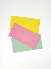 Three pink, yellow and green closed envelopes for money on white background, message concept