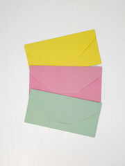 Three pink, yellow and green closed envelopes for money on white background, message concept