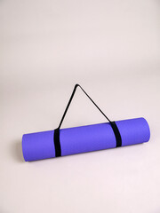Lilac sports yoga mat in roll on grey background with black handle