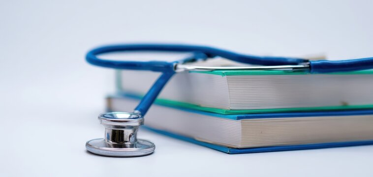 The stethoscope resting on a stack of medical textbooks for healthcare students.