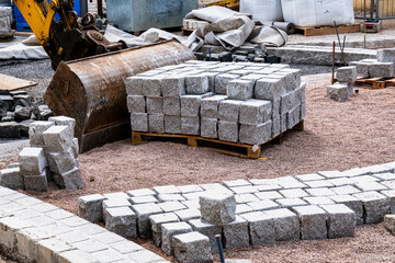 Granite blocks and excavator on a construction site for roadwork. Construction sites like this...