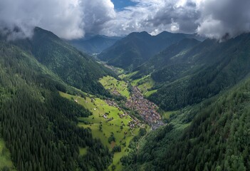 Naklejka premium Serene Mountain Valley with Forest and Cloudy Sky