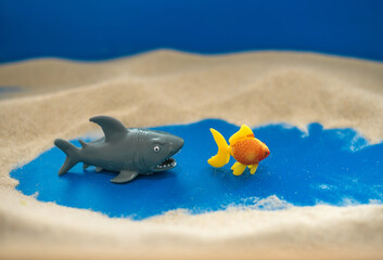 The concept of psychology. Sand
therapy. Figures of two sharks on the sand in a blue
sandbox. Psychology. Therapy. POST-TRAUMATIC
stress disorder. Confrontation. Aggression.