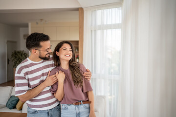 Happy couple embracing and smiling in modern living room