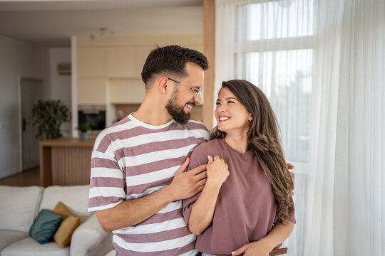 Happy couple embracing and smiling in modern living room