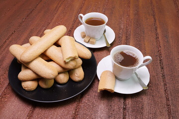 Tazze con tè, savoiardi sardi sul piatto per colazione