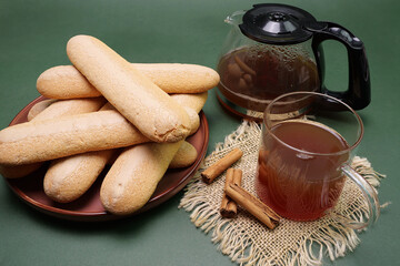 Colazione con savoiardi sardi e tè, bicchiere con tè e cannella sul tovagliolo