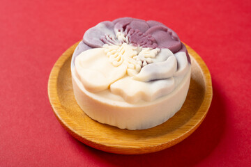 angle view trendy and beautiful flower shape purple and white colors moon cake on a red background