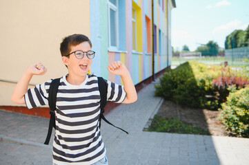 Enthusiastic pupil celebrating back to school outside colorful building