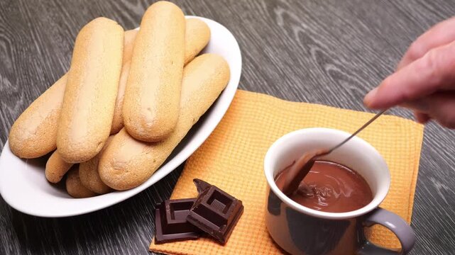 Mescolare la cioccolata nella tazza con un cucchiaino, piatto con biscotti