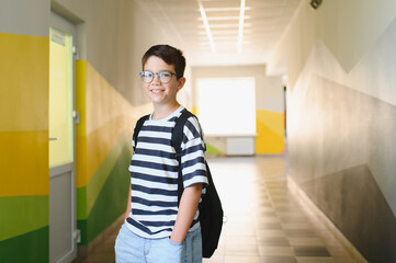 Smiling student wearing backpack standing in school hallway