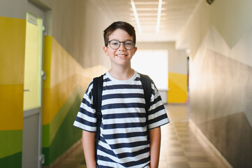 Smiling student wearing backpack standing in school hallway