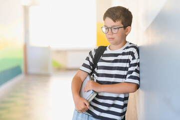 Sad schoolboy crying in school hallway after bullying from classmates