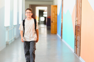 Smiling student walking in school corridor during break time