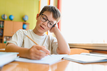 Schoolboy doing homework, learning and studying in classroom