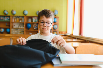 Student opening backpack at school desk getting ready for class
