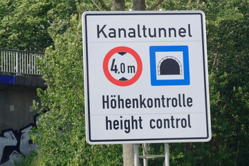 White sign with tunnel height limit near bridge trees