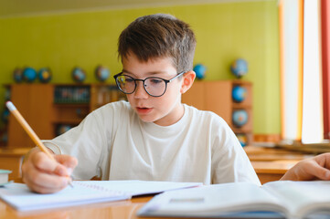 Schoolboy doing homework and studying in classroom