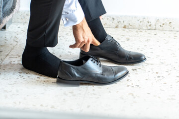 Getting ready for an important meeting, a man carefully puts on his polished black dress shoes...