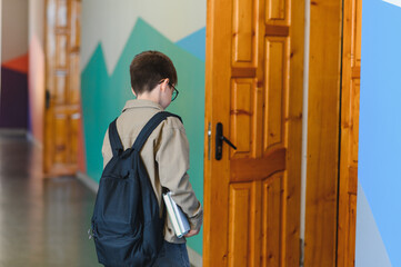 Student entering classroom carrying backpack and books, back to school concept
