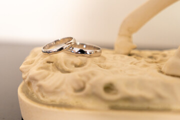 Elegant silver wedding rings resting on an intricately carved surface