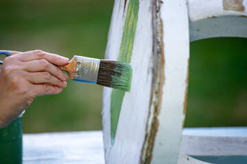 Painting a wooden furniture outdoors, an eco-friendly re-use business.