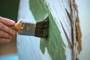 Painting a wooden furniture outdoors, an eco-friendly re-use business.