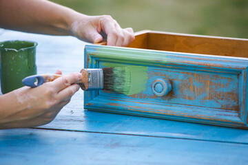 Painting a wooden furniture outdoors, an eco-friendly re-use business.