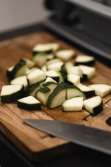 Fresh, diced zucchini on a wooden cutting board, ready to cook in natural light