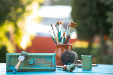 Painting a wooden furniture outdoors, an eco-friendly re-use business.