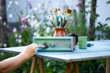 Painting a wooden furniture outdoors, an eco-friendly re-use business.