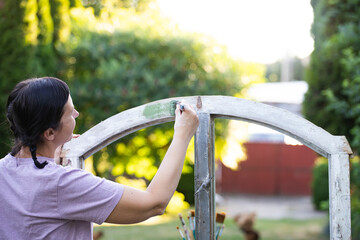 Womanpainting a wooden furniture outdoors, an eco-friendly re-use business.