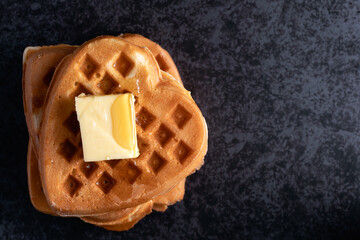 Stack of heart shaped waffles with butter and syrup